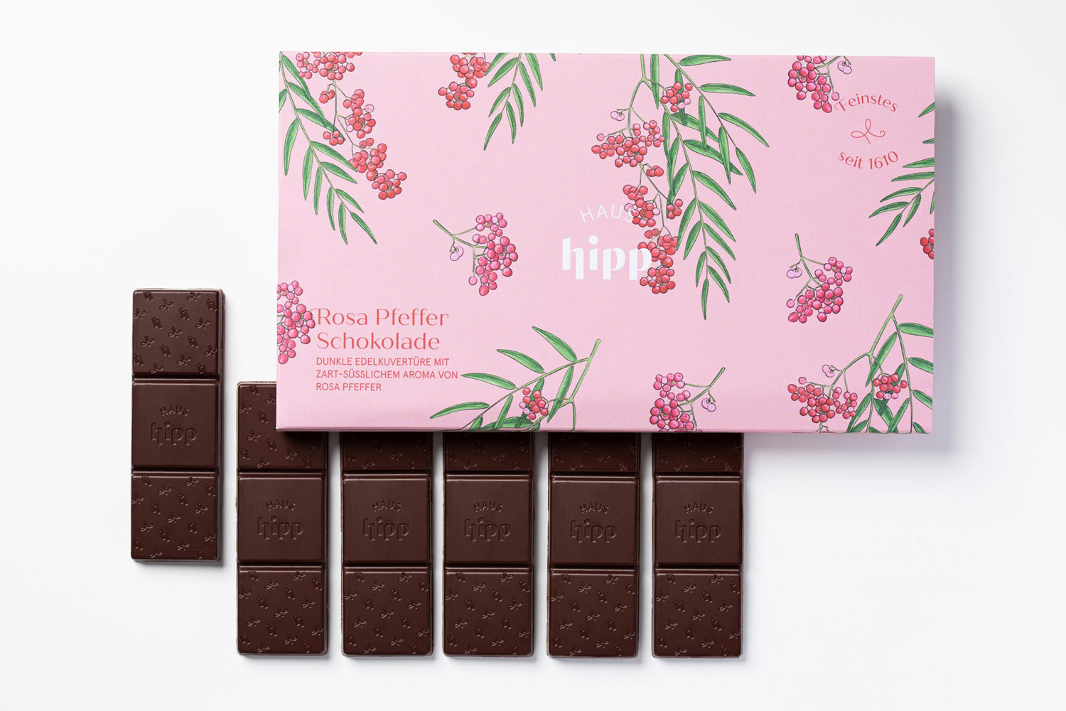 Dark chocolate bar beside pink packaging with a pepper motif
