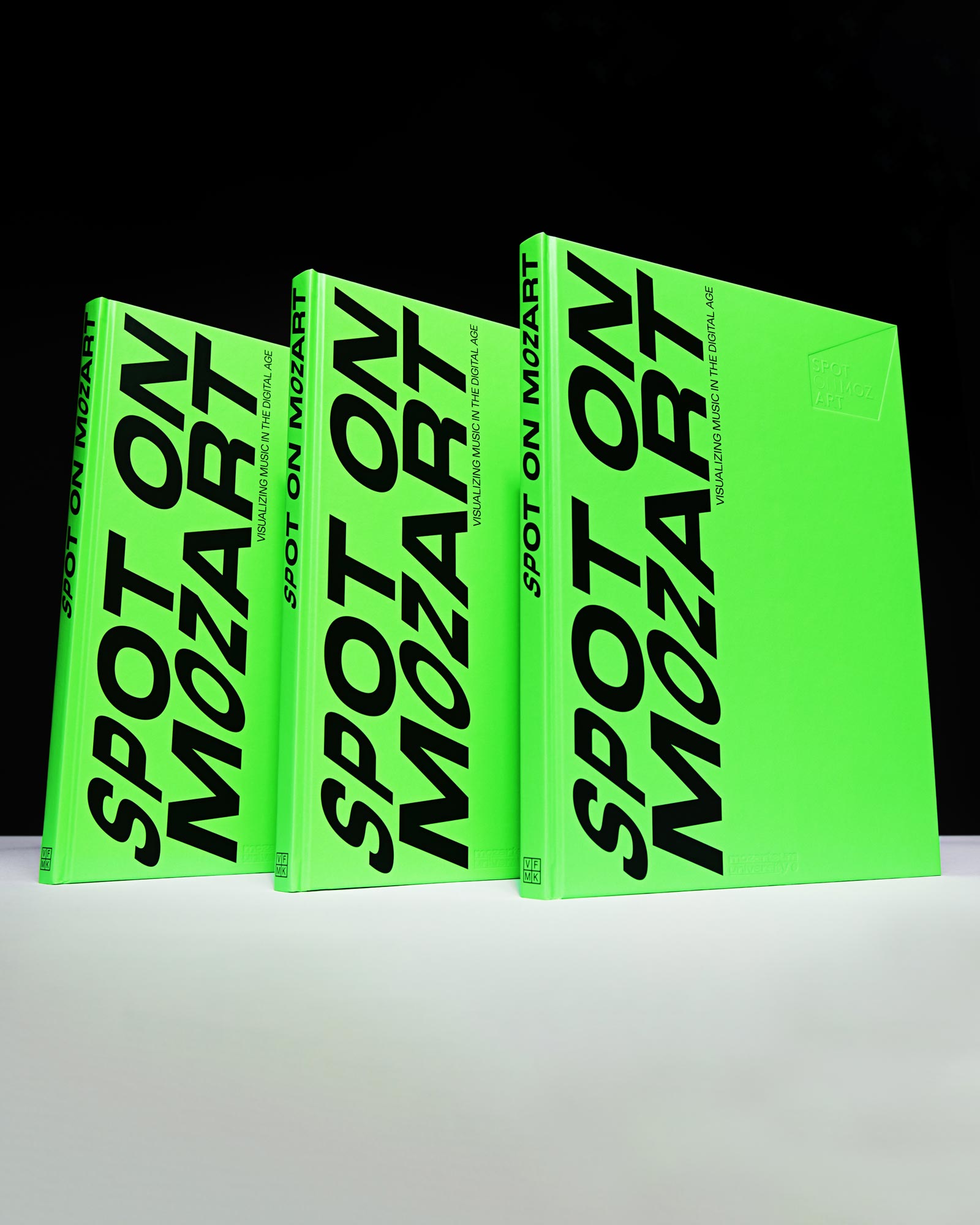 Three upright Spot on Mozart books with black typography on neon green