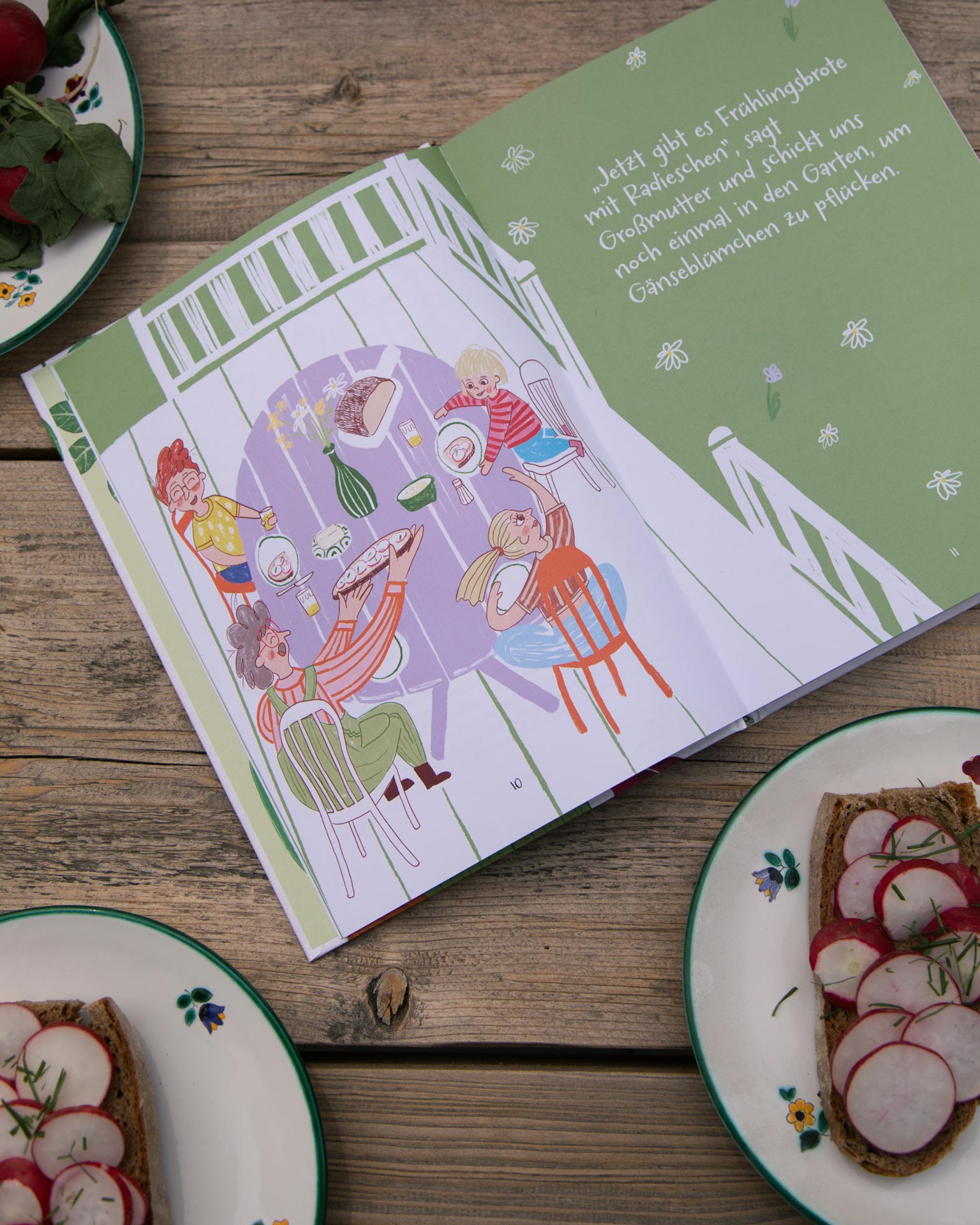 Illustrated recipe page beside open sandwiches on a wooden table