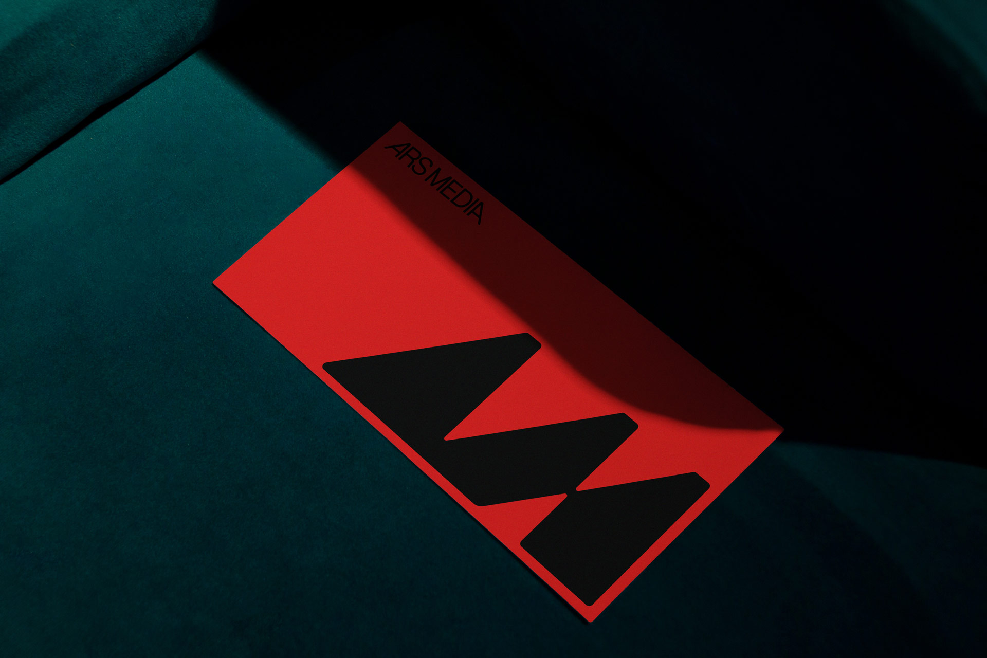 Detail of a red Ars Media card with a black monogram