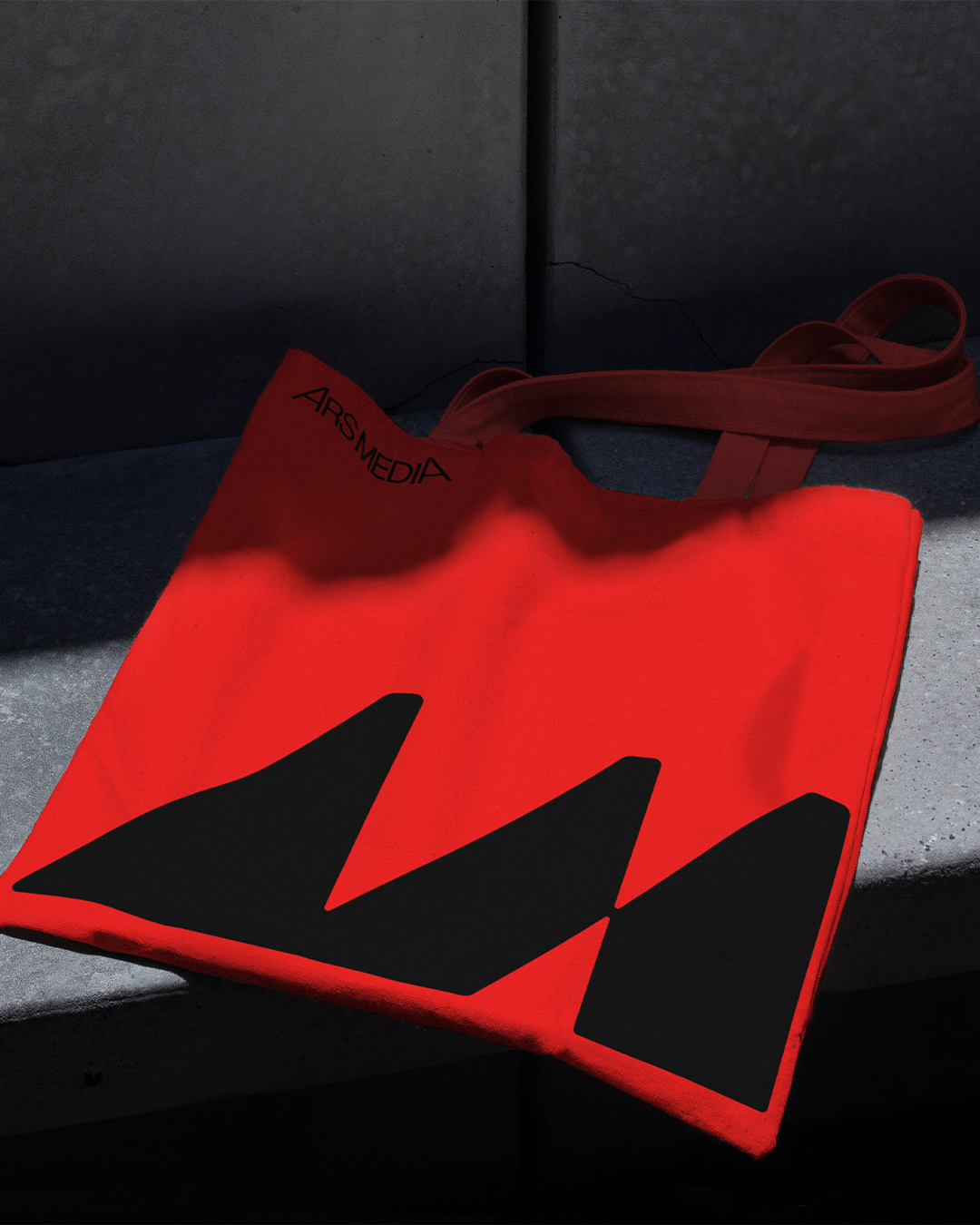 Red tote bag with a large black Ars Media symbol