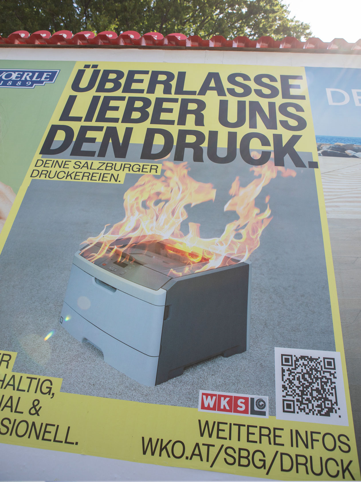Plakat der Salzburger Druckereien mit brennendem Drucker an einer Außenwerbefläche