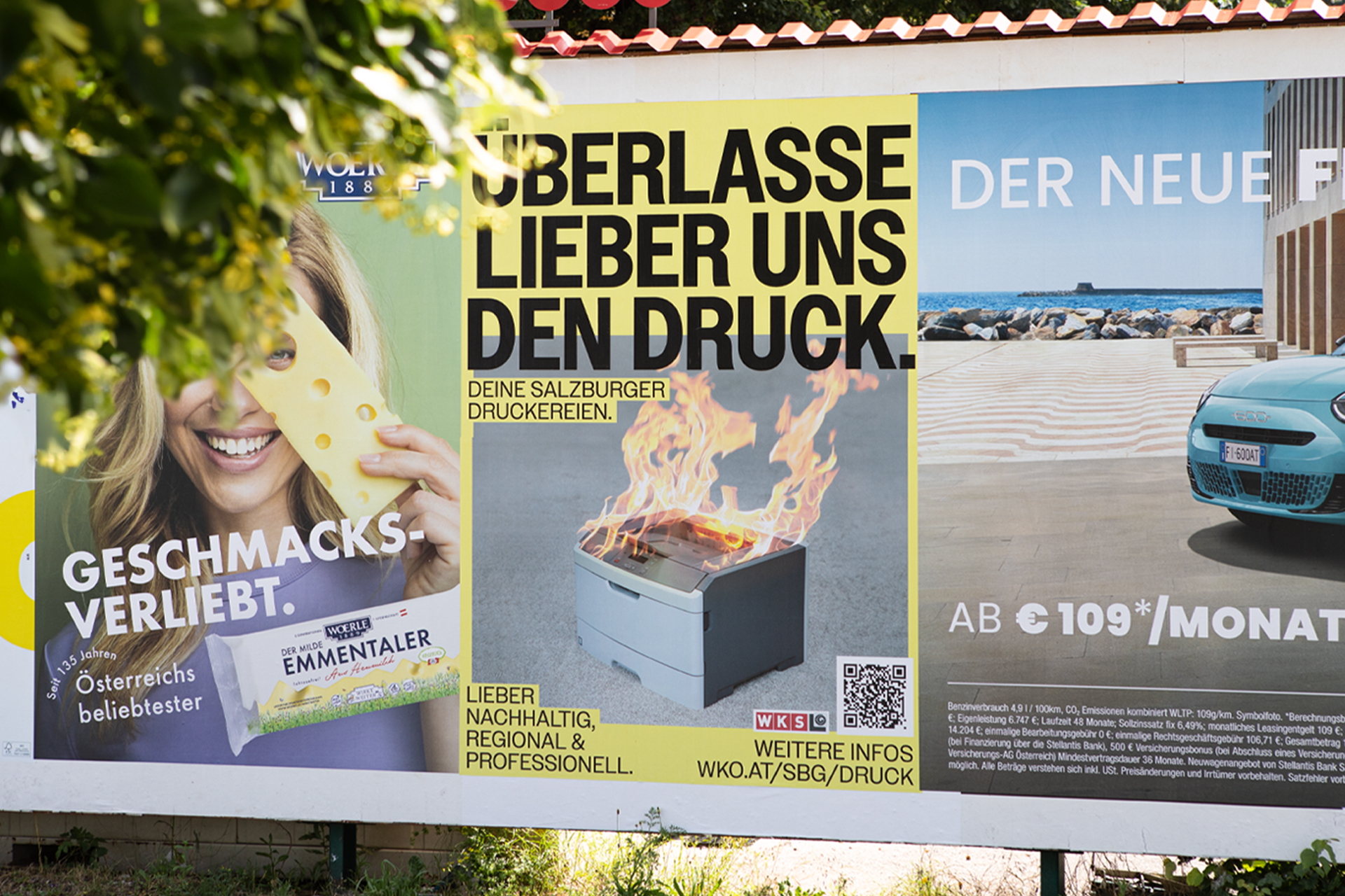 Gelbes Druckerei-Kampagnenplakat zwischen weiteren Außenwerbeplakaten