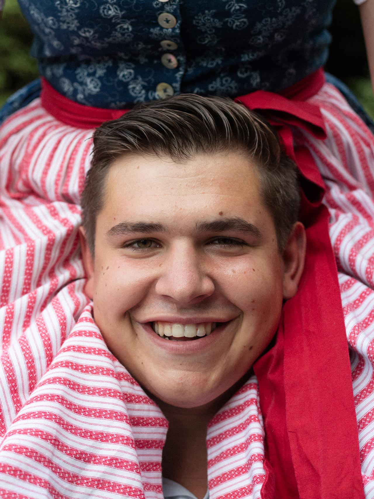 Portrait of a smiling young man framed by traditional clothing