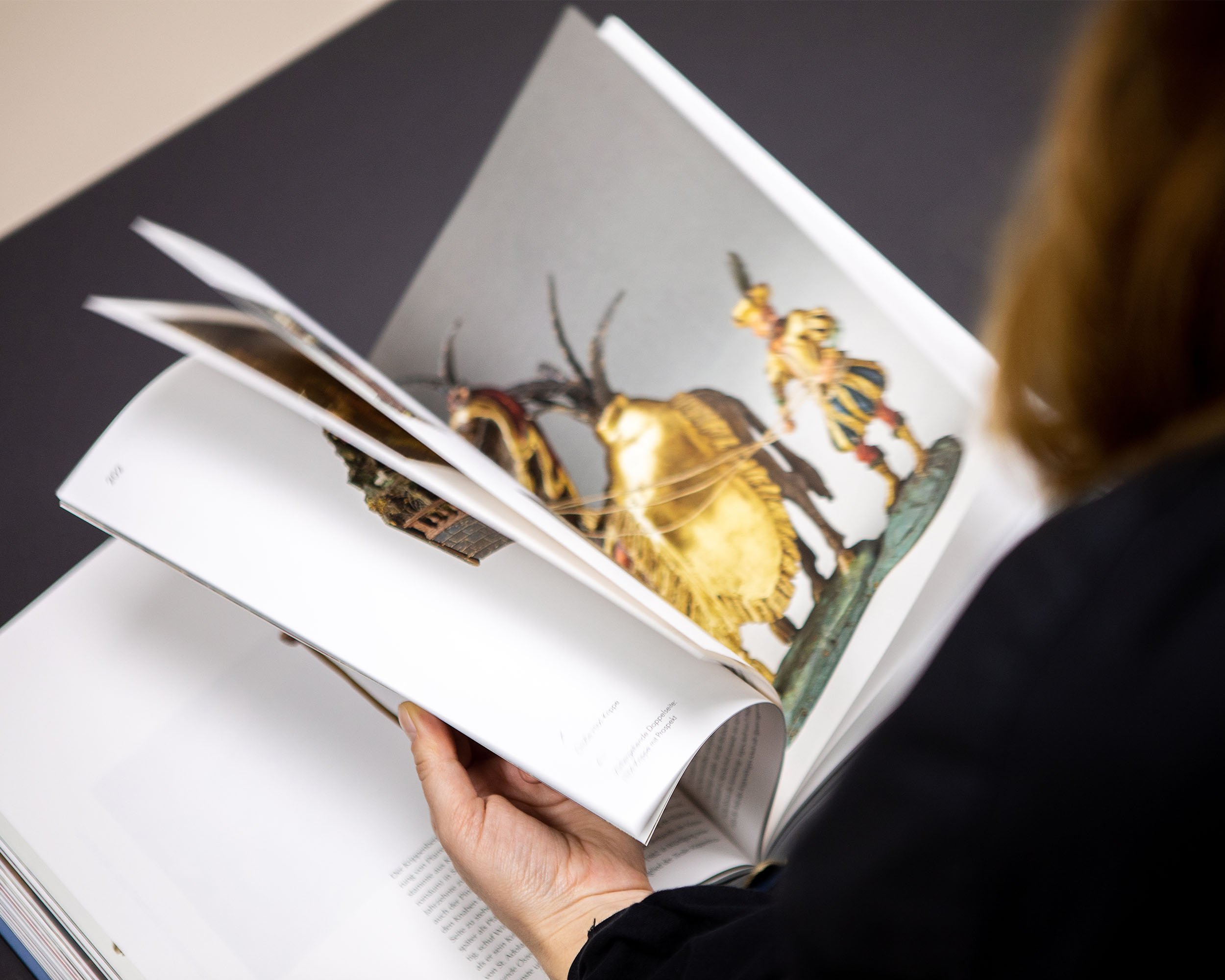 Person browsing the large-format book about Salzburg nativity art