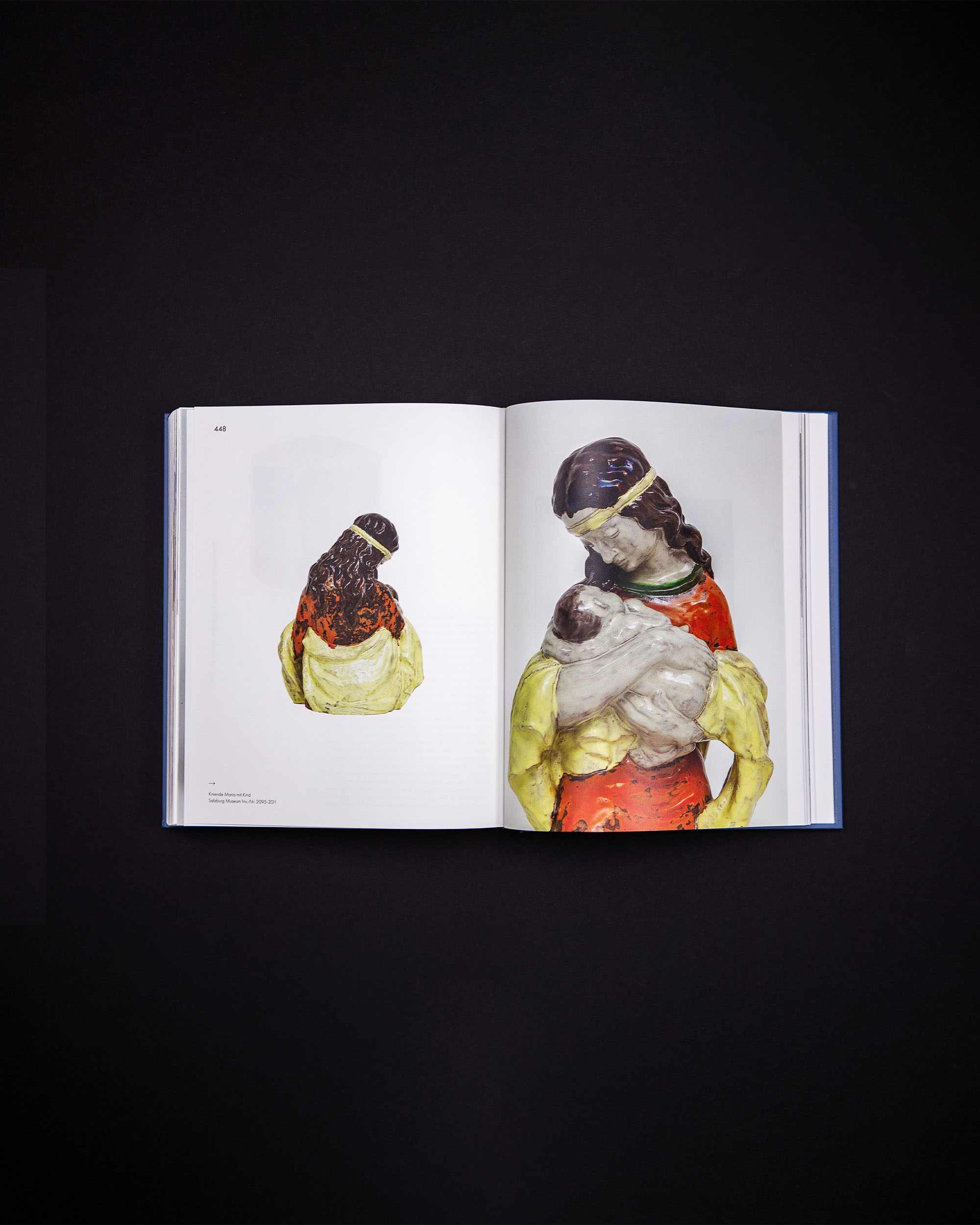 Book spread with two large photographs of painted nativity figures