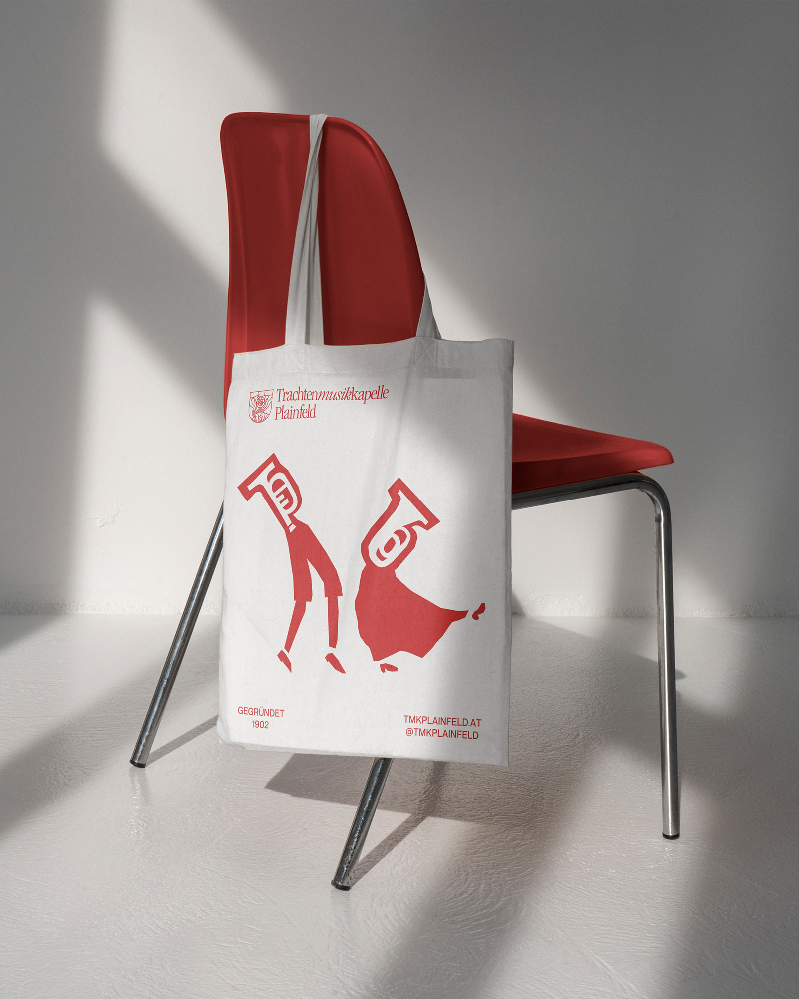 White tote bag with red musician characters hanging from a chair