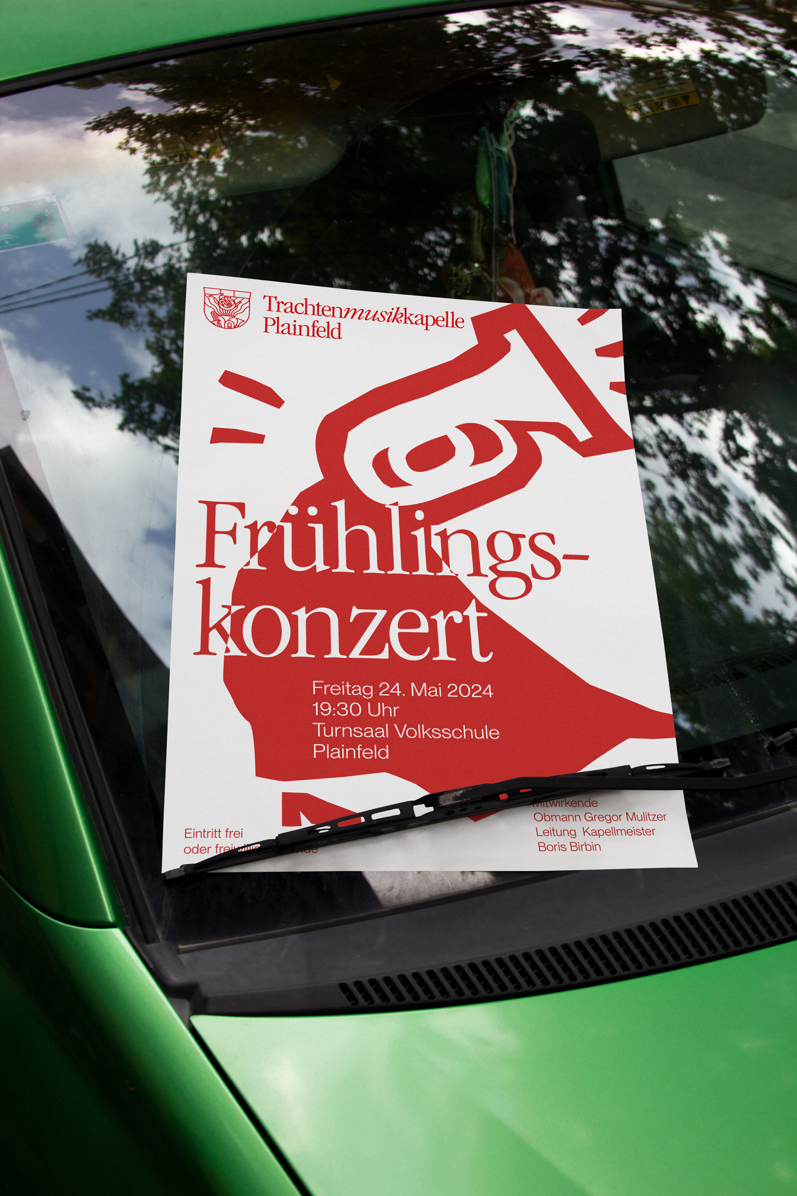 Red-and-white spring concert poster on a green car
