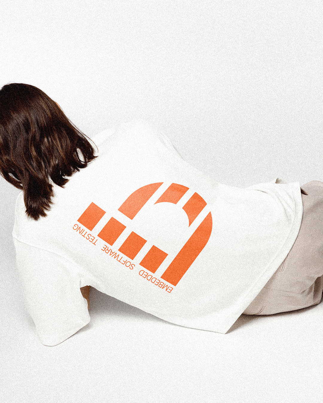 Person wearing a white T-shirt with a large orange bitcrush symbol
