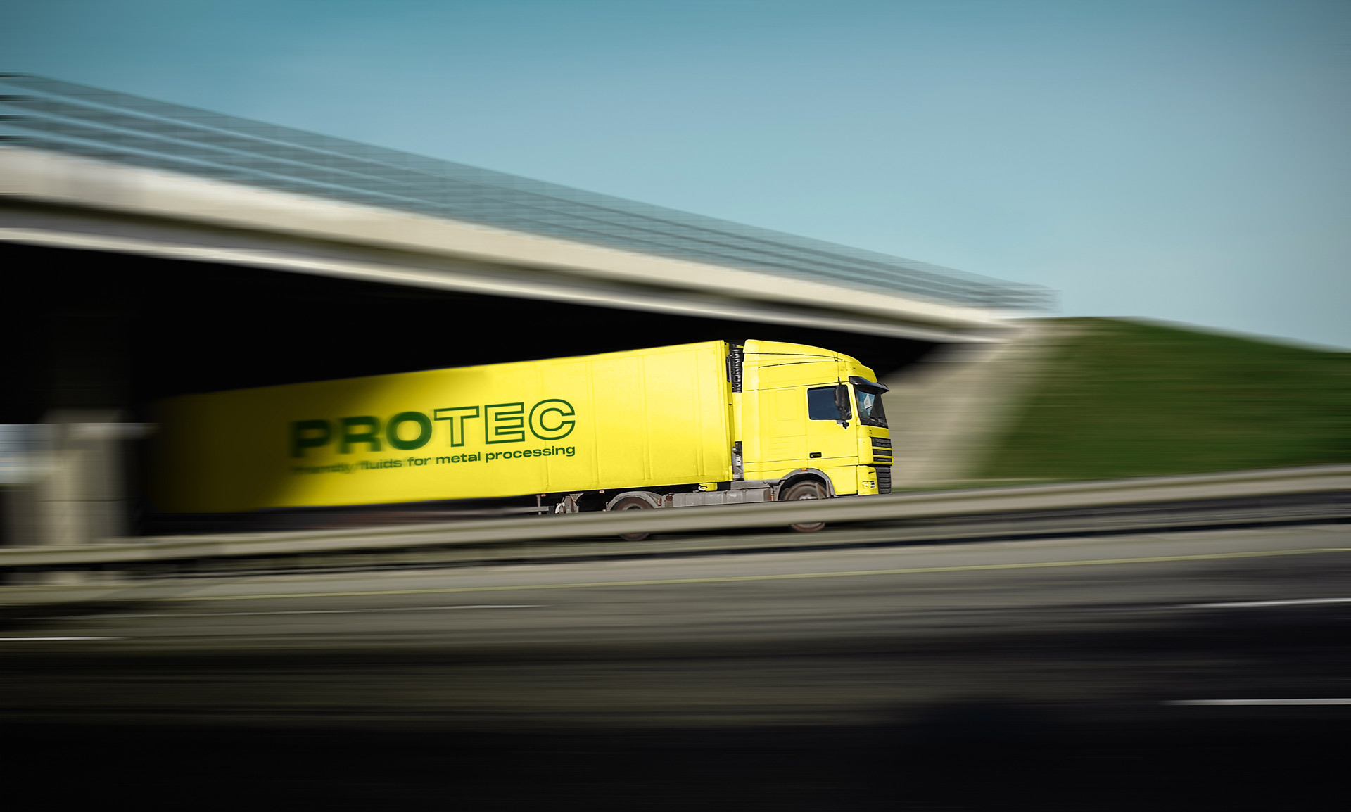 Yellow truck with PROTEC lettering on a road