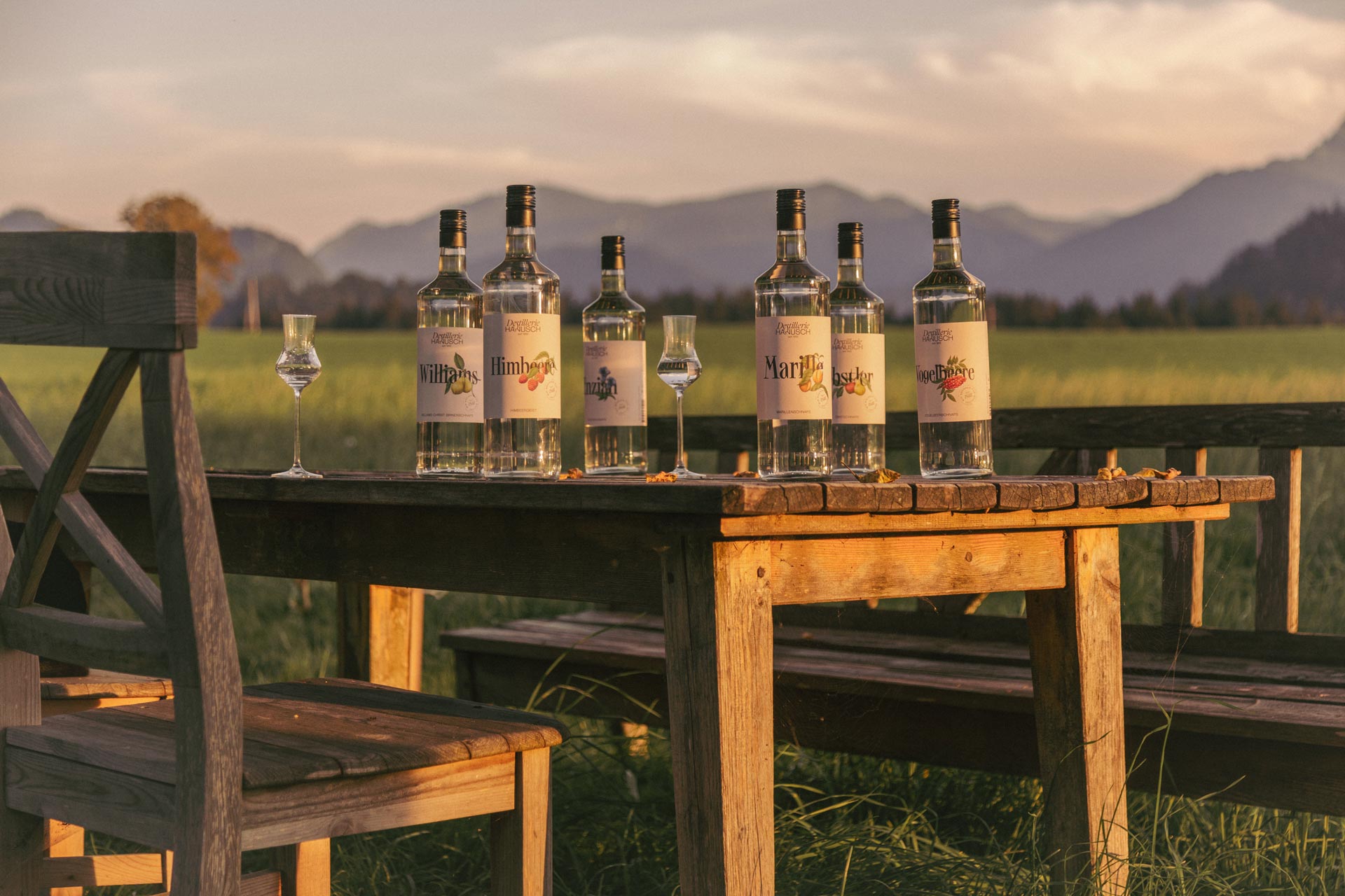 Hanusch spirits on a wooden table against a mountain landscape