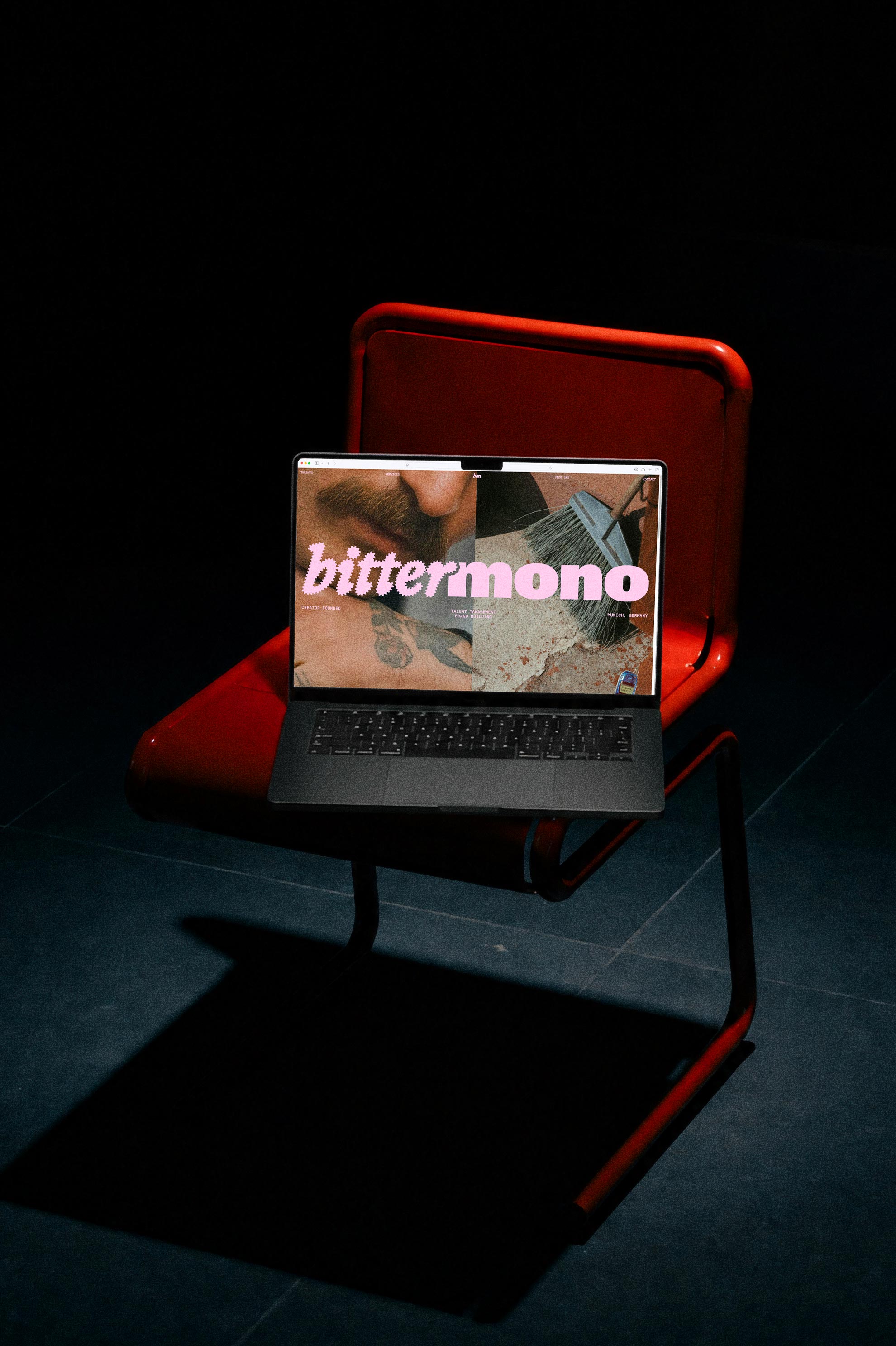 Laptop displaying the Bittermono website on a red chair in the dark