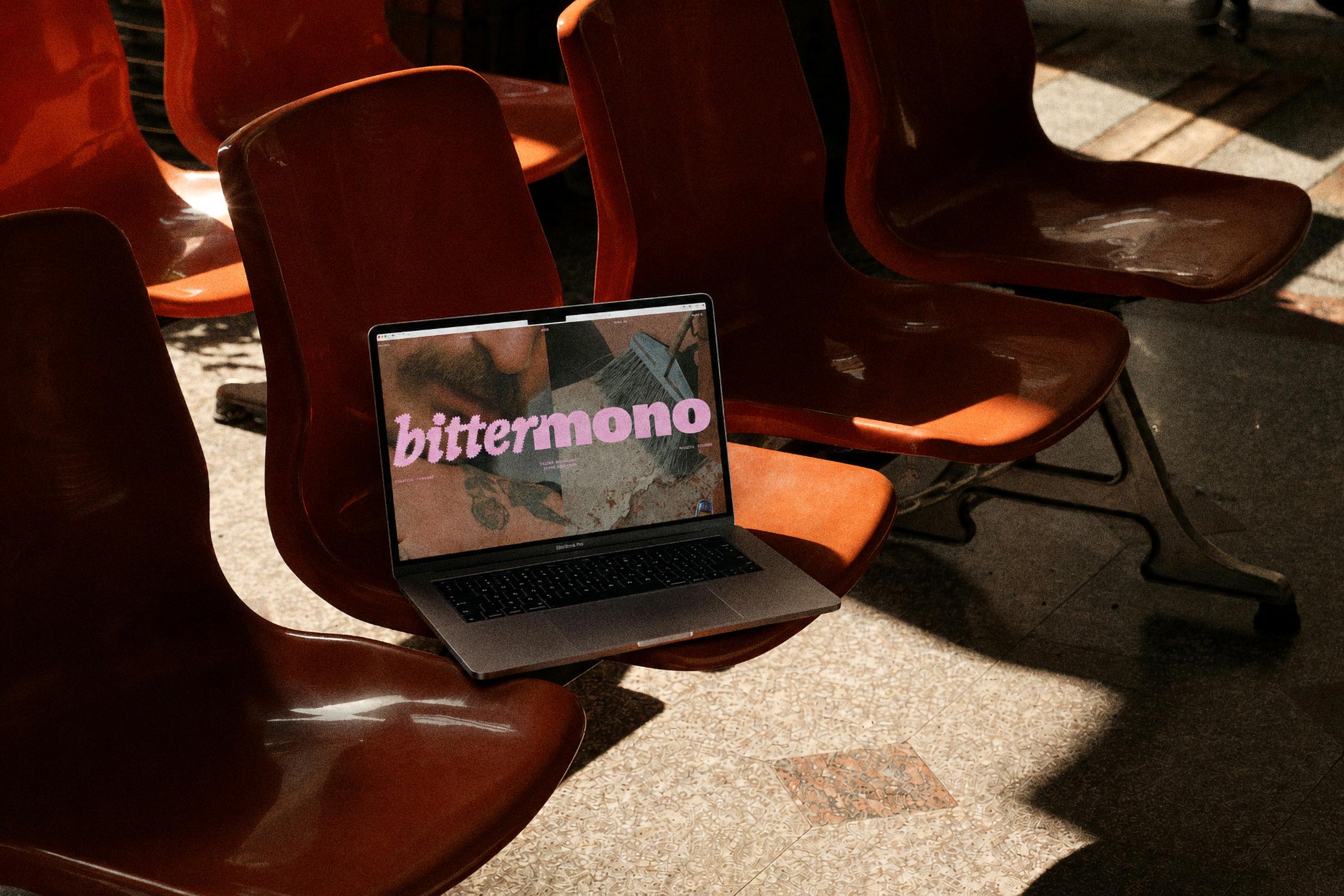 Laptop displaying the Bittermono website on a row of red cinema seats