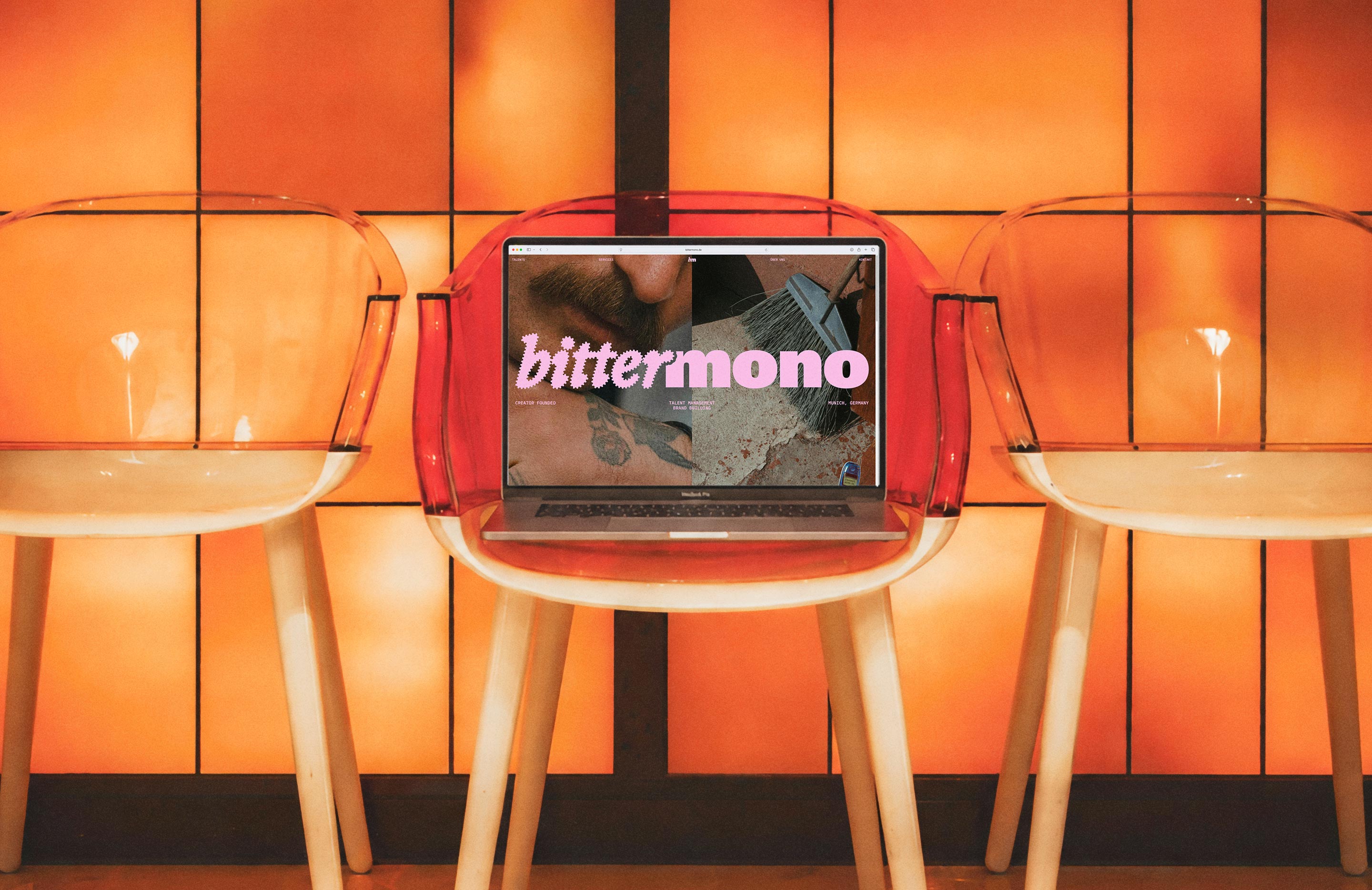 Bittermono website on a laptop among chairs against an orange wall