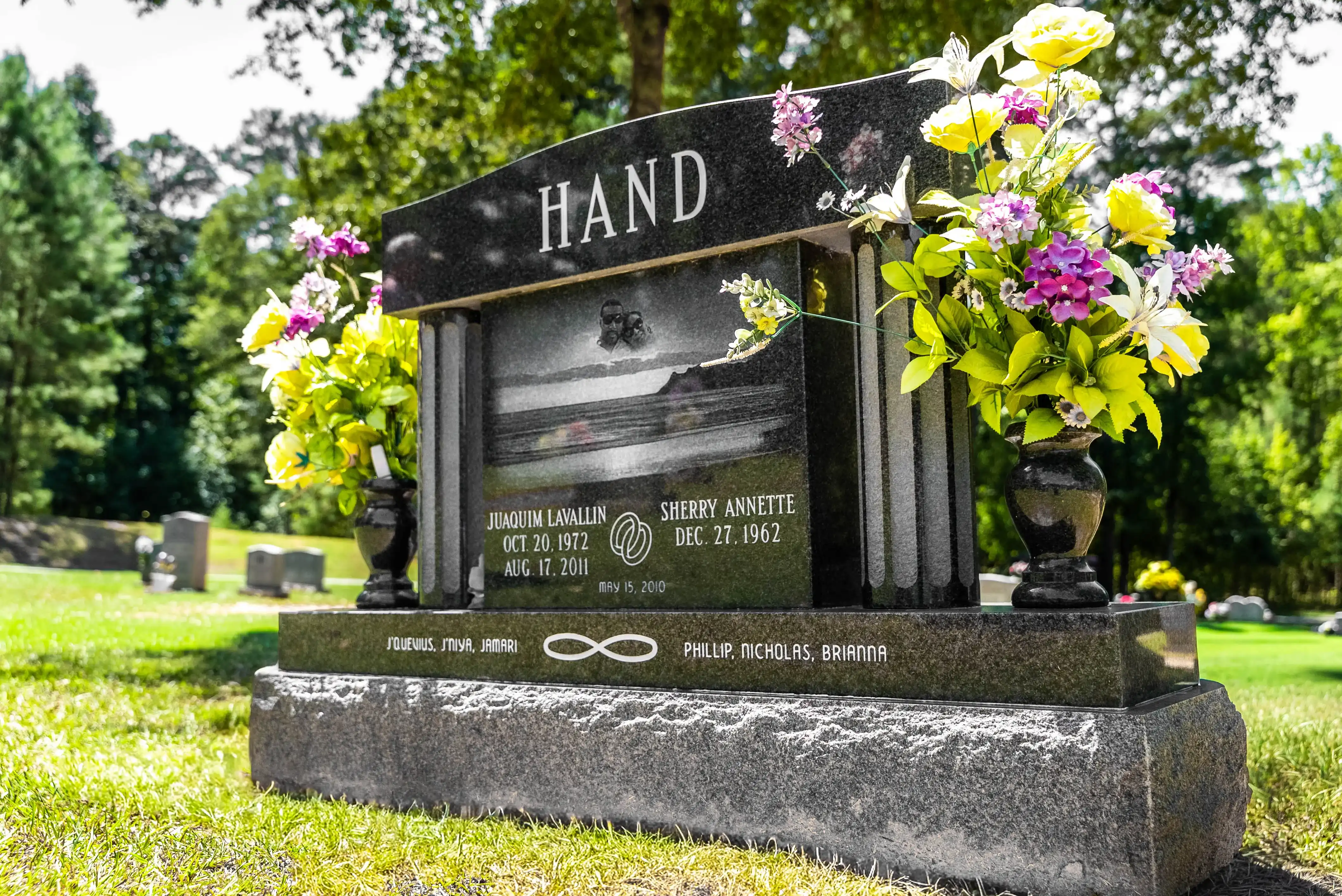 Black granite upright monument with an etched photo panel and flower vases on each side
