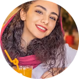 Jeune femme souriante avec des cheveux bouclés portant un foulard rose.