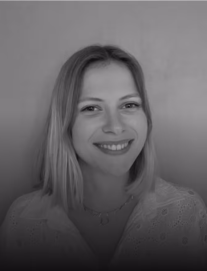 Jeune femme souriante aux cheveux blonds portant une blouse légère à motifs brodés.