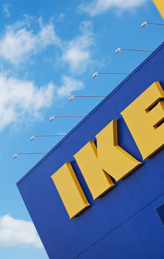 Façade bleue avec lettres jaunes IKEA sous un ciel bleu partiellement nuageux.