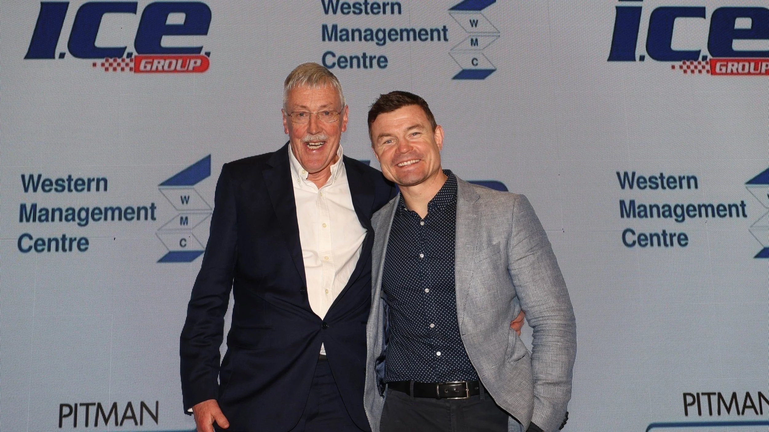 Two men posing and smiling in front of a backdrop featuring ICE Group and Western Management Centre logos.