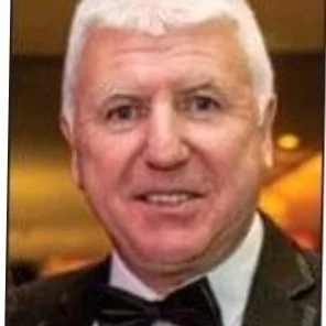 Portrait of an older man with white hair wearing a black tuxedo and bow tie.