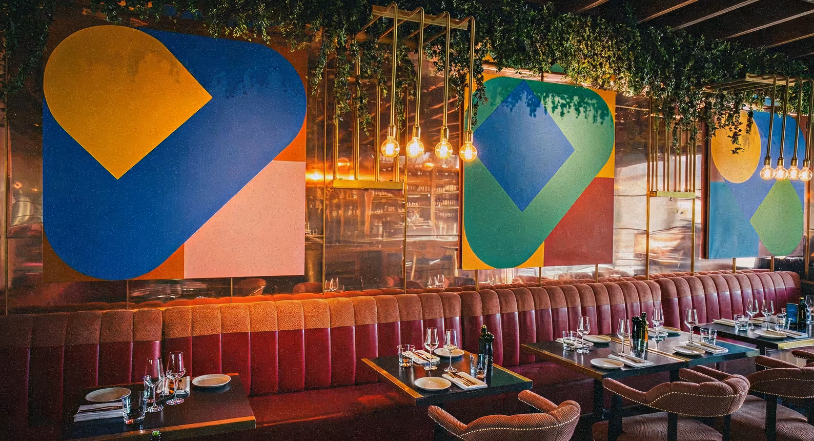 Bold geometric artworks above a long velvet banquette in the dining room at Angelina's