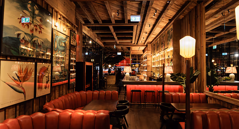 Red leather banquettes and botanical prints under a reclaimed timber ceiling at Mama Yo