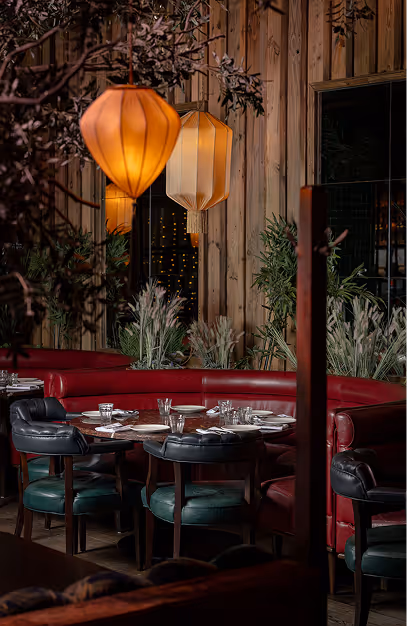 Silk lanterns above a red banquette and green leather chairs in the dining room at Mama Yo