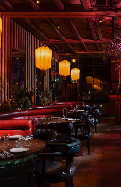 Red leather banquettes and silk lanterns above dark timber tables at Mama Yo