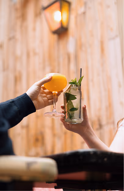 Orange coupe and a mint highball toasted against the timber wall at Mama Yo