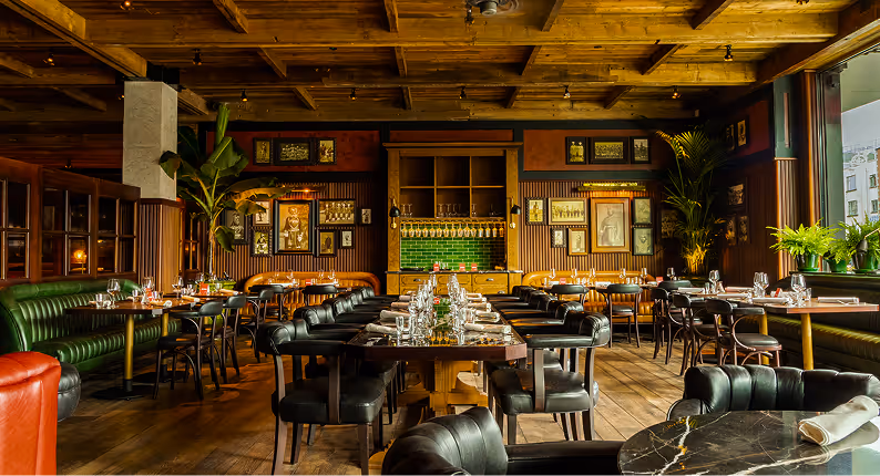 Green leather banquettes and a long communal table beneath timber beams at Doolally