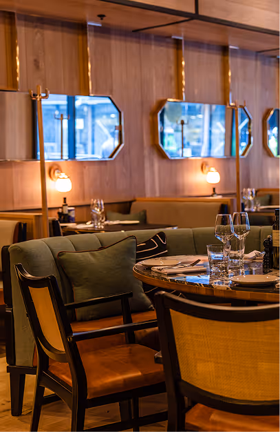 Green banquettes, rattan chairs and octagonal mirrors in the oak-panelled dining room at Isabelle's