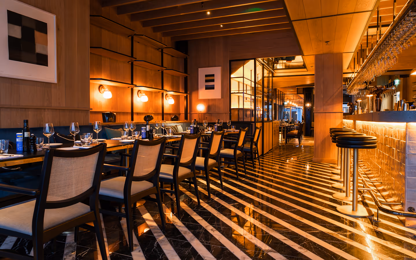 Striped marble floor, cane-back chairs and bar stools running the length of Isabelle's dining room