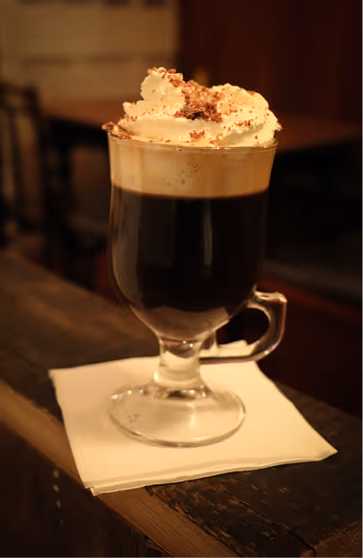 Irish coffee topped with cream in a stemmed glass on the bar at Mary's Bar & Hardware