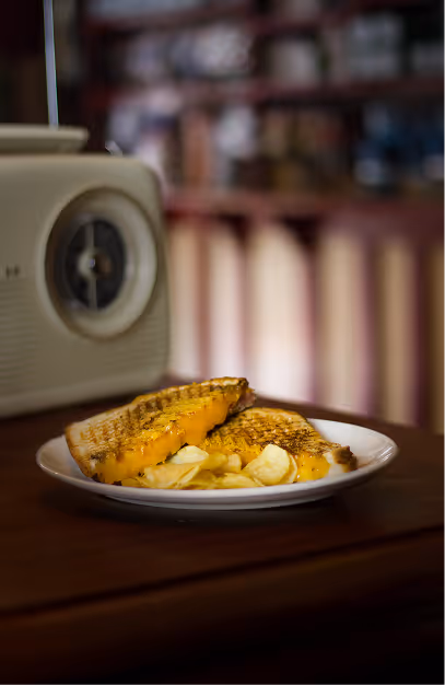 Toasted cheese sandwich served with crisps beside a vintage radio at Mary's Bar & Hardware