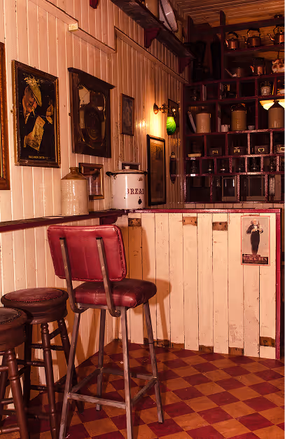 Red vinyl bar stool on a checkerboard floor beside vintage hardware drawers at Mary's Bar & Hardware