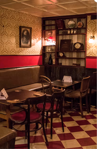 Bentwood chairs and a leather banquette on a red checkerboard floor in the snug at Mary's Bar & Hardware