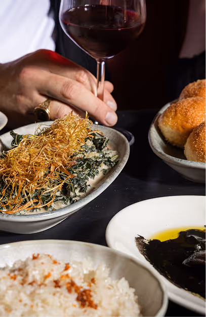 Creamed greens with crispy potato, bread rolls and rice served with red wine at Kaldero