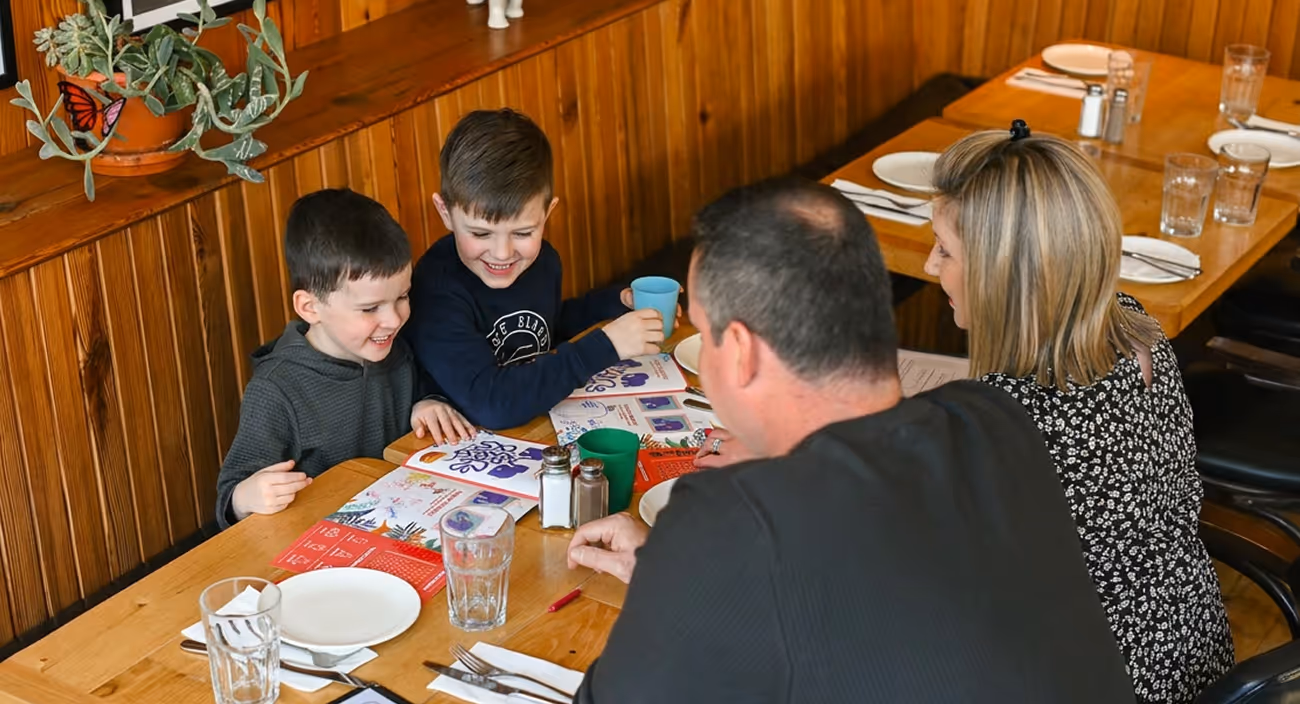 Two young boys colouring kids' menus at a family table in a wood-panelled dining room
