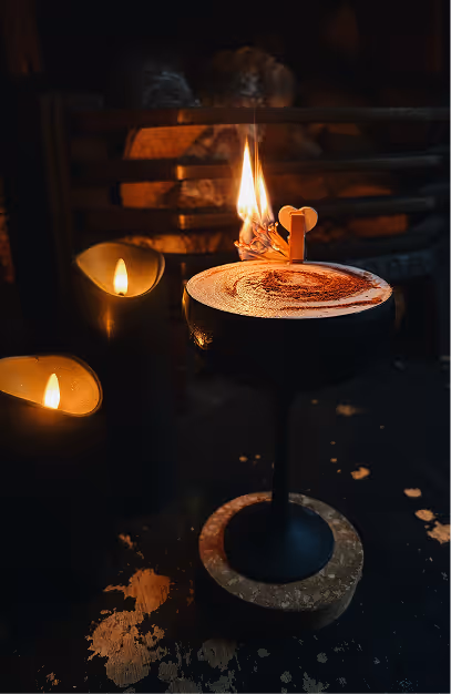 Coupe cocktail with a flaming garnish beside candles at Peruke & Periwig