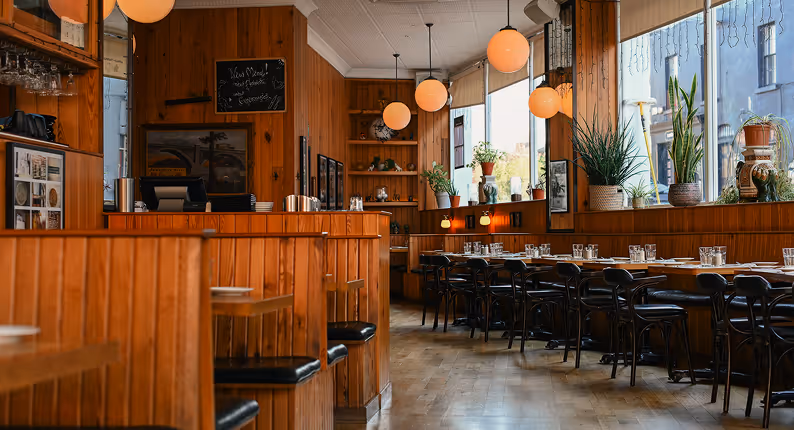 Timber-panelled dining room with globe pendants and bentwood chairs at Elephant & Castle