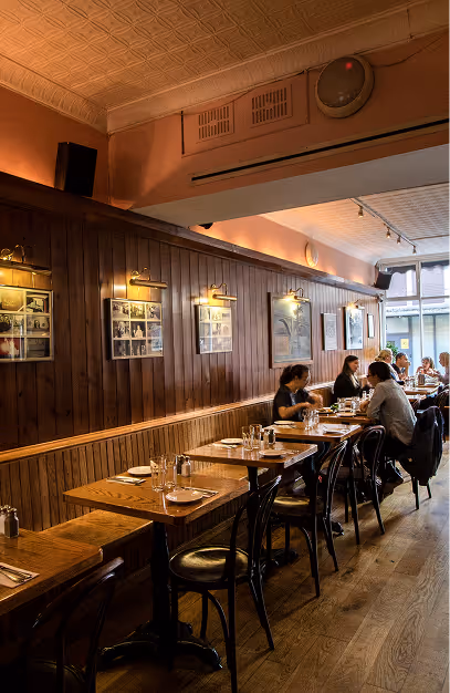 Timber-panelled dining room with bentwood chairs and framed pictures, guests dining by the window at Elephant & Castle