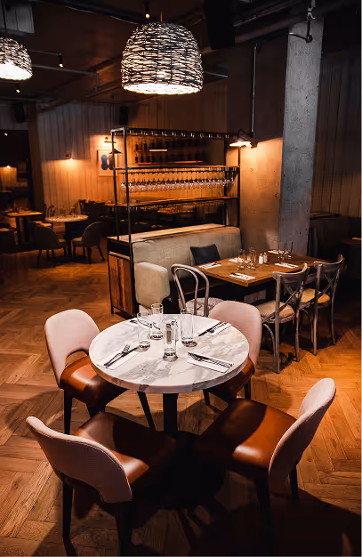 Marble table and leather chairs beneath woven pendant lights in the dining room at Elephant & Castle