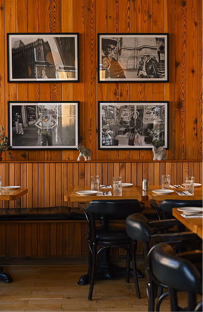Framed black-and-white prints above the banquette and bentwood chairs at Elephant & Castle
