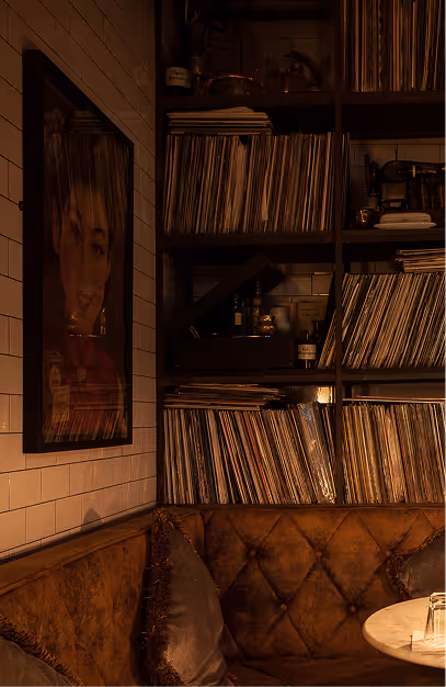 Shelves of vinyl records above a buttoned leather banquette at Vintage Cocktail Club