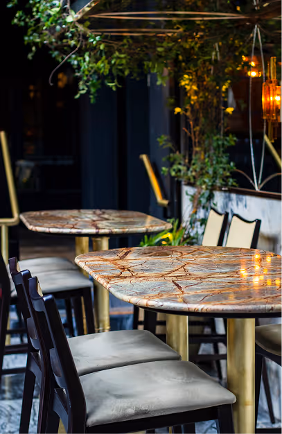 Marble-topped high tables on brass bases under trailing greenery at The Grayson