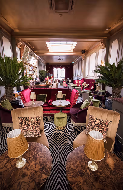 Pink and burgundy velvet armchairs on a chevron carpet in the bar room at Stella Cocktail Club