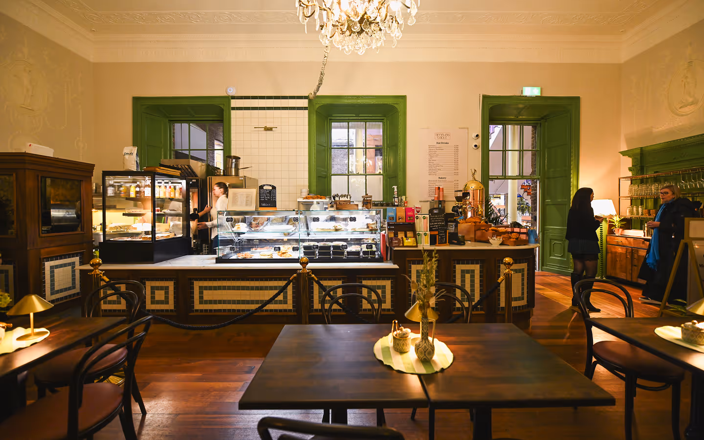Green-framed deli counter and bentwood chairs under a chandelier in the cafe at Amelia's Table