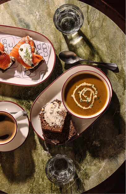 Smoked salmon toast, soup and buttered brown bread with coffee on a green marble table at Amelia's Table