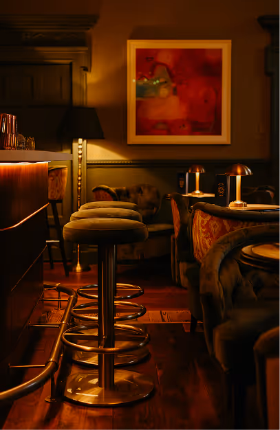 Brass bar stools with olive velvet seats beneath a red abstract painting at The Stapleton
