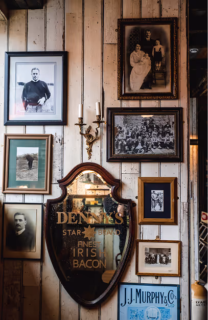 Vintage advertising mirror framed by old family portraits at John's Bar & Haberdashery